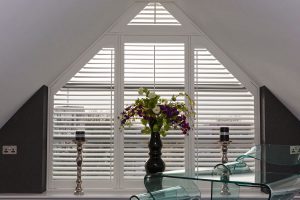 Triangular window frame with wooden shutters in loft at Chelmsford home